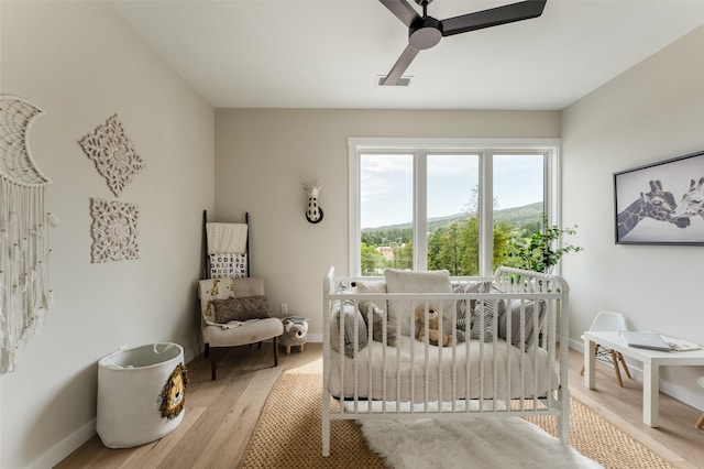 bedroom featuring wood finished floors, visible vents, baseboards, and ceiling fan
