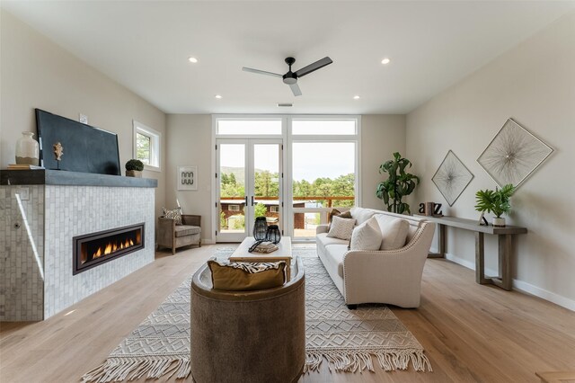 living room featuring baseboards, recessed lighting, light wood-style floors, a ceiling fan, and a tile fireplace