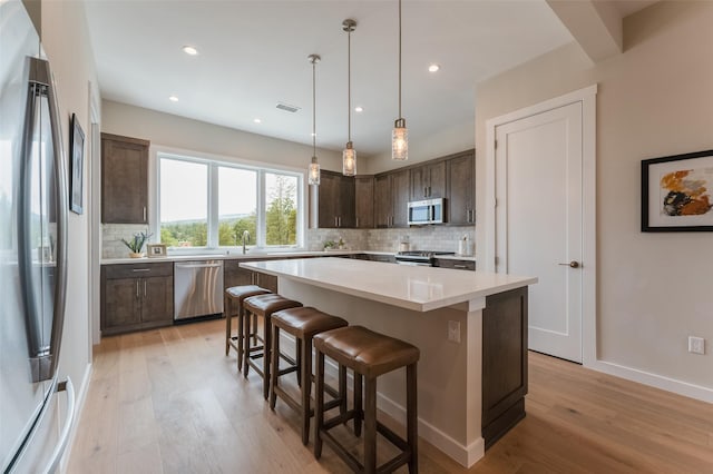kitchen featuring light wood finished floors, stainless steel appliances, visible vents, and dark brown cabinetry
