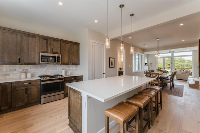 kitchen with appliances with stainless steel finishes, dark brown cabinets, and light wood-style floors