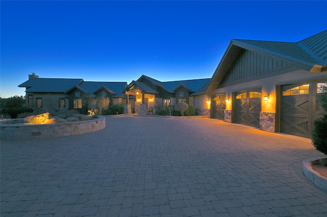 craftsman-style home featuring stone siding, board and batten siding, curved driveway, and a garage