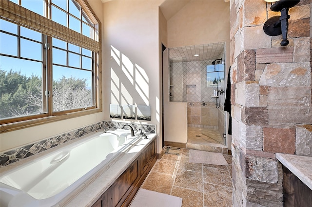 full bathroom with a bath, stone tile floors, and tiled shower