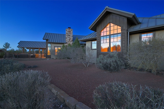 view of property exterior with stucco siding, a chimney, a standing seam roof, and metal roof