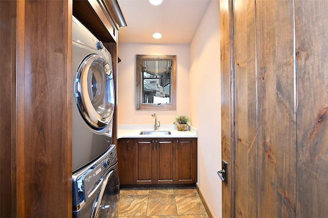 laundry area with a sink, baseboards, stacked washer / dryer, recessed lighting, and cabinet space
