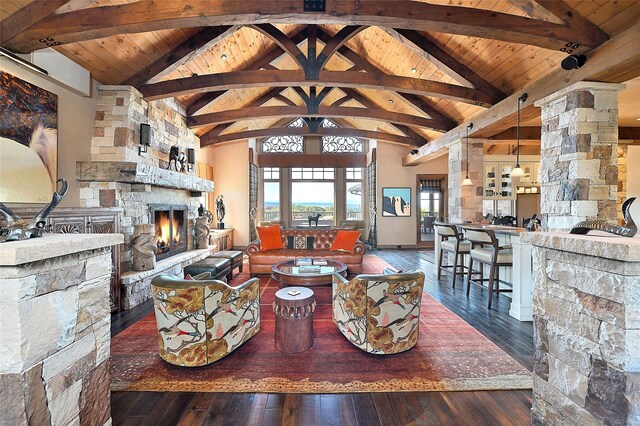 living room with beamed ceiling, a stone fireplace, wood ceiling, and hardwood / wood-style flooring