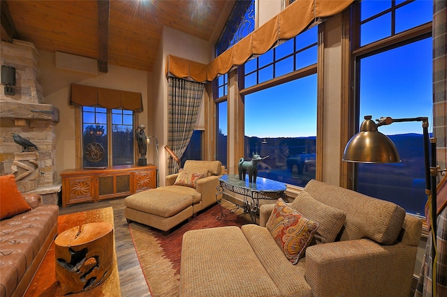 living area with wood finished floors, high vaulted ceiling, and wooden ceiling