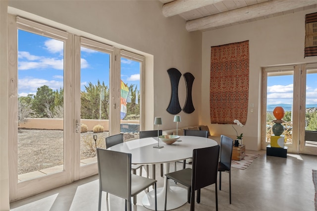 dining room featuring wooden ceiling, a towering ceiling, beamed ceiling, and finished concrete flooring