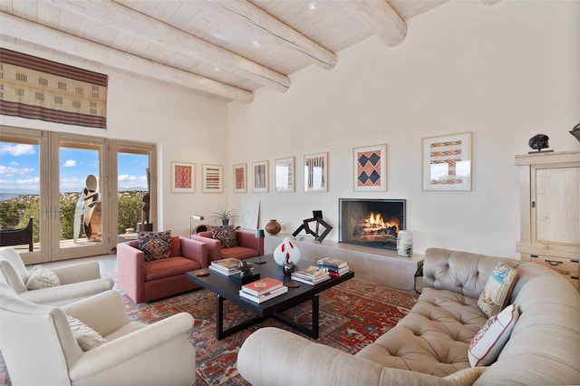 living area featuring wood ceiling, beamed ceiling, a high ceiling, and a lit fireplace