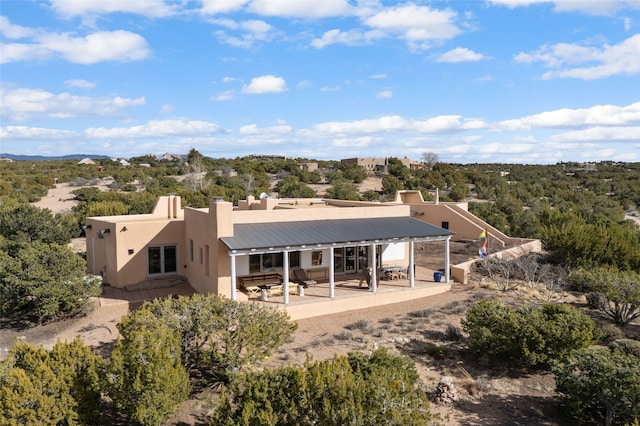back of property with metal roof, a patio area, and stucco siding