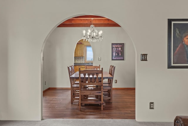 11 Sierra Lejana, Santa Fe, NM 87508 - dining space featuring wood finished floors, arched walkways, beamed ceiling, baseboards, and a chandelier