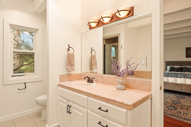 ensuite bathroom with ensuite bathroom, vanity, baseboards, toilet, and tile patterned flooring