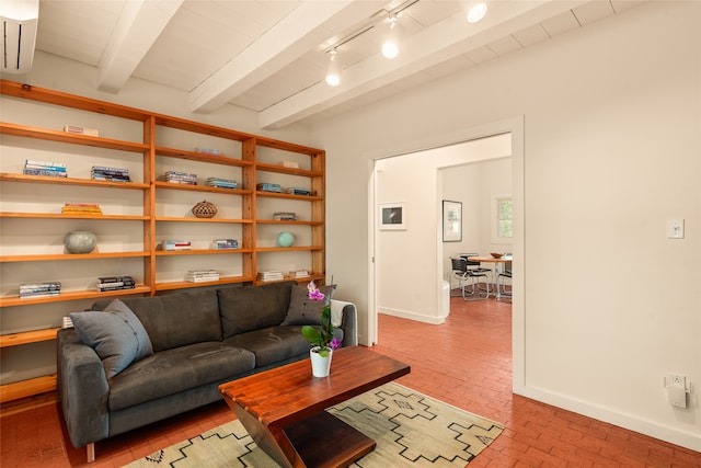 living room featuring brick floor, beam ceiling, baseboards, and track lighting