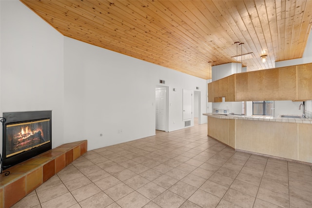 kitchen featuring tile counters, light tile patterned floors, wood ceiling, and a sink
