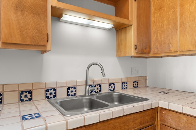 kitchen featuring tile counters, a sink, and brown cabinets