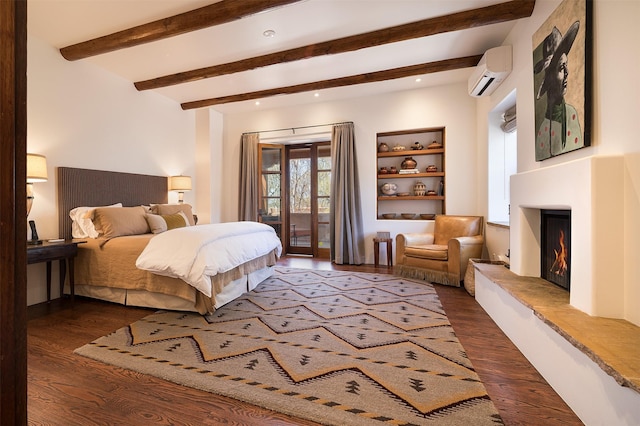 6 El Nido Ln, Santa Fe, NM 87506 - bedroom with a wall unit AC, a fireplace, beam ceiling, dark wood-style floors, and access to exterior