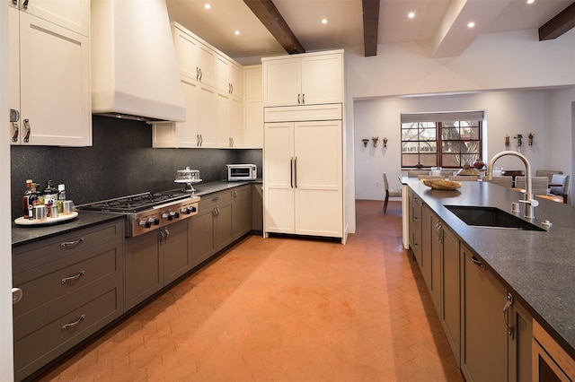 6 El Nido Ln, Santa Fe, NM 87506 - kitchen featuring paneled built in fridge, a sink, stainless steel gas cooktop, tasteful backsplash, and custom exhaust hood