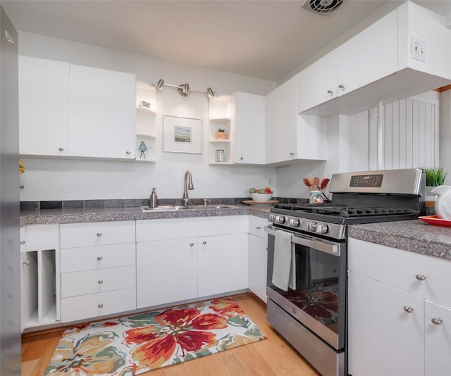 kitchen with open shelves, a sink, light wood-type flooring, white cabinetry, and stainless steel gas range oven