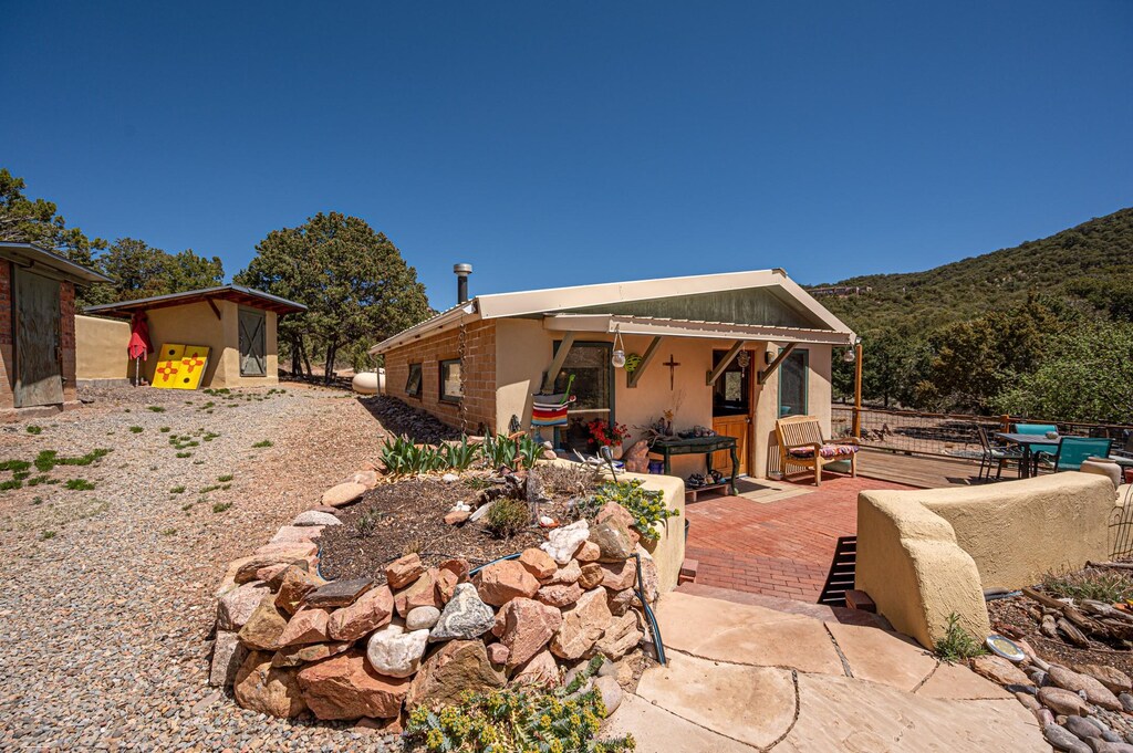 back of house featuring a mountain view, an outbuilding, a patio, stucco siding, and a storage unit