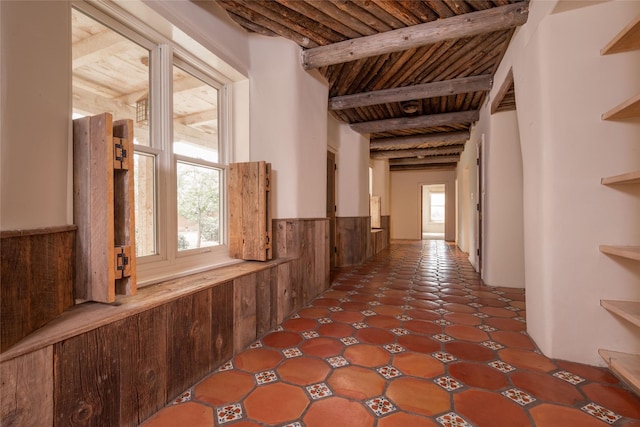 hallway with wood ceiling, a wainscoted wall, and beamed ceiling