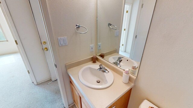 half bath featuring a textured wall and vanity