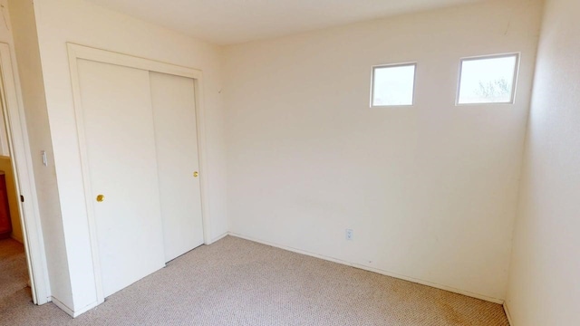 unfurnished bedroom with light carpet and a closet