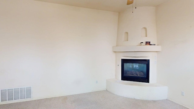 unfurnished living room featuring a glass covered fireplace, ceiling fan, carpet, baseboards, and visible vents