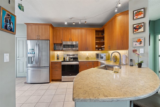 kitchen with open shelves, decorative backsplash, brown cabinets, a peninsula, and appliances with stainless steel finishes