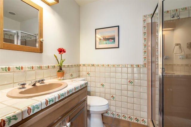 full bathroom with a shower stall, tile patterned floors, toilet, vanity, and tile walls