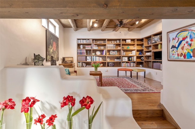 sitting room featuring beamed ceiling, wooden ceiling, wood finished floors, and ceiling fan