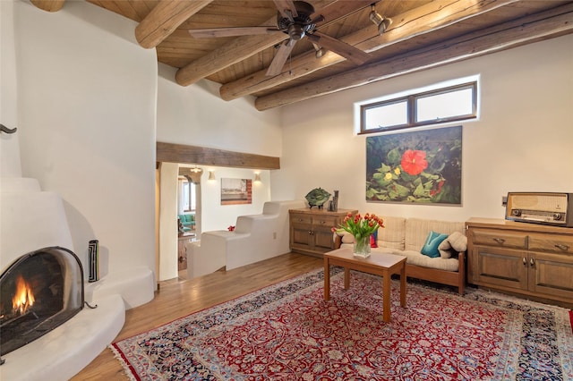 living room featuring beamed ceiling, wood finished floors, stairs, ceiling fan, and wooden ceiling
