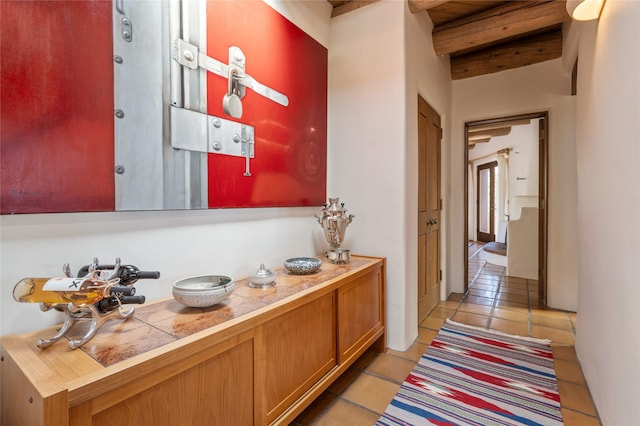 hallway featuring beamed ceiling and light tile patterned floors