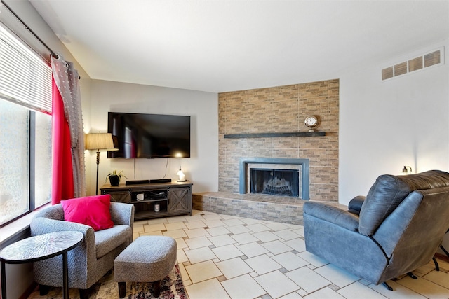 living room featuring a healthy amount of sunlight, a brick fireplace, and visible vents
