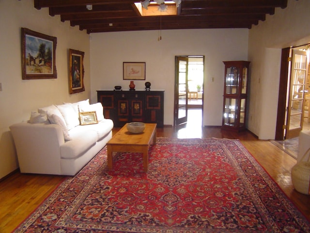 living area featuring beam ceiling and wood finished floors