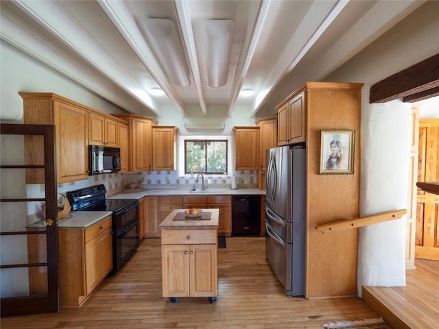 kitchen with light wood-type flooring, a center island, a sink, and black appliances