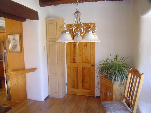 dining space with hardwood / wood-style floors, an inviting chandelier, and beamed ceiling