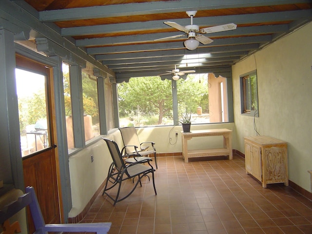 sunroom featuring ceiling fan, beamed ceiling, and plenty of natural light