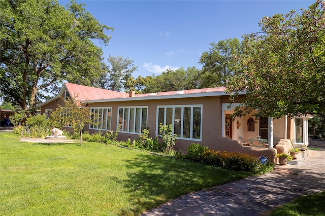 back of property featuring metal roof, a yard, and stucco siding