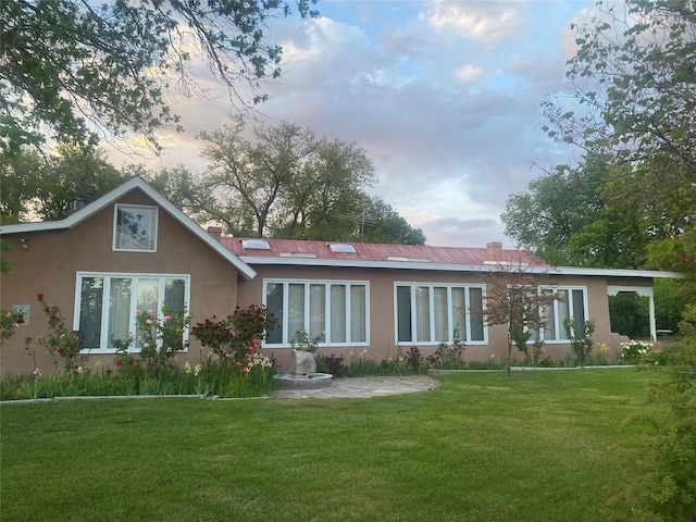 rear view of house with a lawn and stucco siding