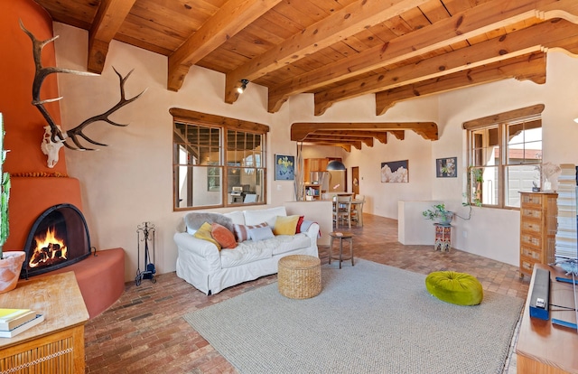 living room with brick floor, beam ceiling, wood ceiling, and a lit fireplace