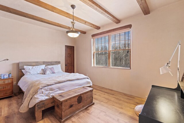 bedroom featuring beamed ceiling and light wood-type flooring