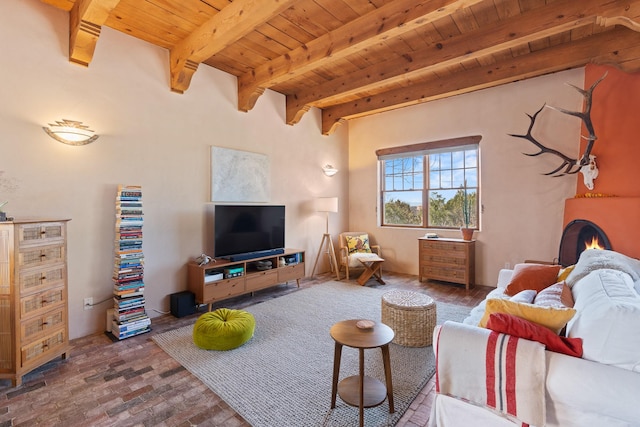 living room with wood ceiling, brick floor, a warm lit fireplace, and beamed ceiling