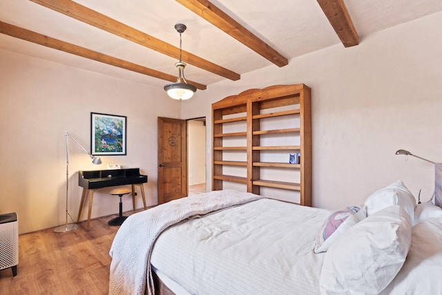bedroom with wood finished floors and beam ceiling