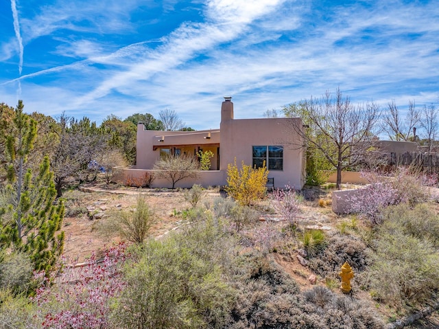 back of property with a chimney and stucco siding