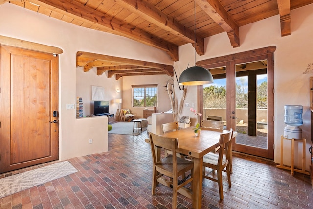 dining room featuring wood ceiling, brick floor, french doors, and beam ceiling