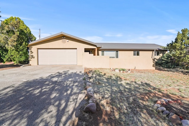 ranch-style home with stucco siding, driveway, metal roof, and a garage