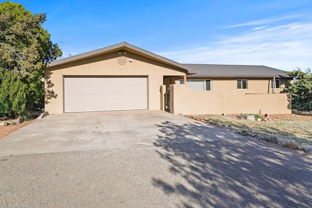 single story home featuring concrete driveway, an attached garage, metal roof, and stucco siding