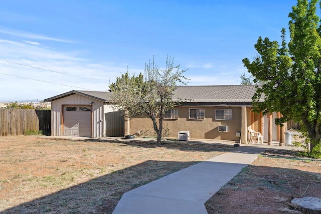 ranch-style home featuring fence, metal roof, and stucco siding
