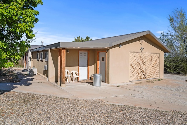 exterior space with stucco siding, an attached garage, concrete driveway, and a patio