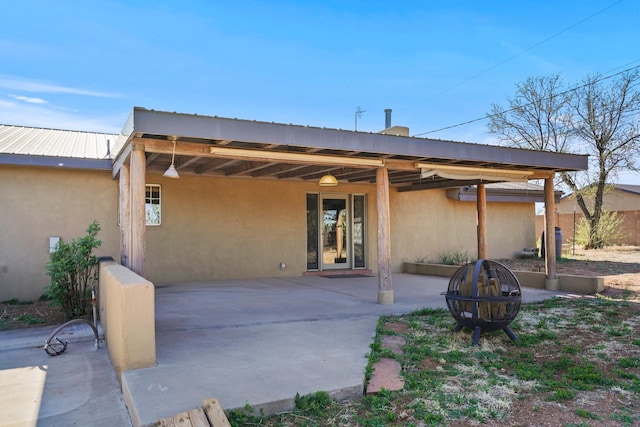 rear view of house featuring a patio area, an outdoor fire pit, and stucco siding