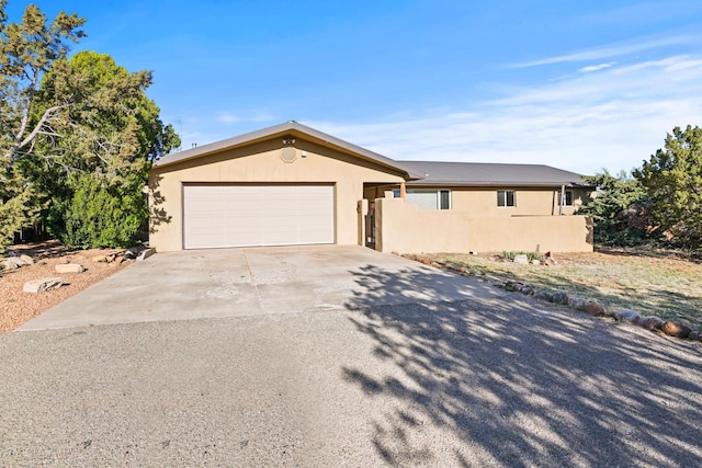 ranch-style house with stucco siding, an attached garage, and driveway
